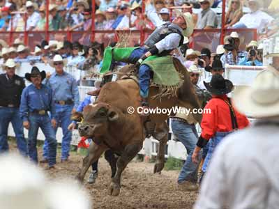 A bull rider in green chaps and a bull riding vest