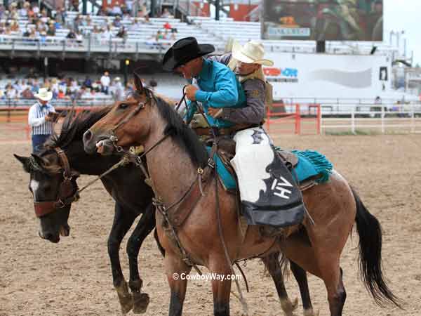 Saddle bronc rider Dusty Hausauer gets off on a pickup man Saddle bronc rider Dusty Hausauer gets off on a pickup man