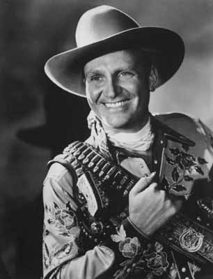 Singer/actor Gene Autry posing with a revolver, gun belt, and holster