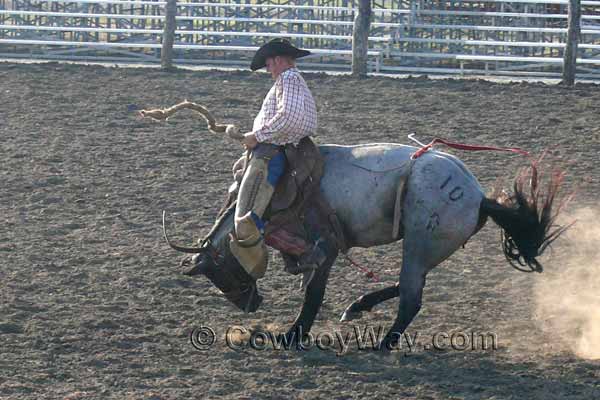 A bronc rider and his ranch saddle go over a bronc's neck