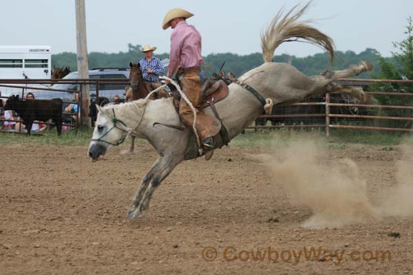 A gray bucking horse bucks in an arena