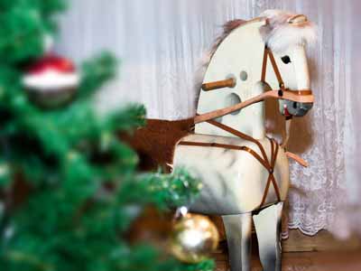 A large wooden rocking horse by a Christmas tree