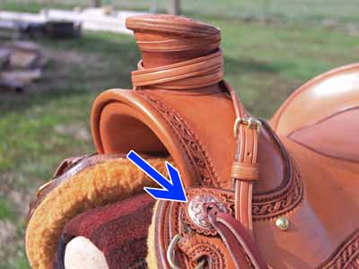 A slotted concho at the front of a saddle near the fork