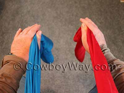 Begin tying the wild rag knot with the tails of the wild rag at your front