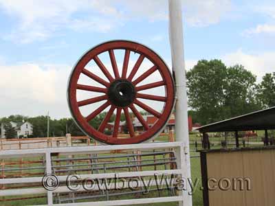 A wagon wheel as decor at a ranch gate