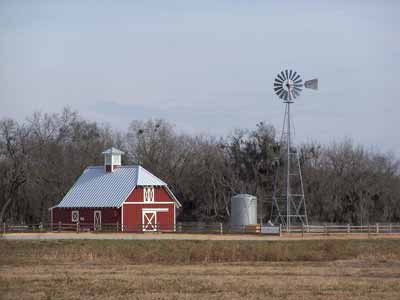 A windmill in a beautiful farm setting