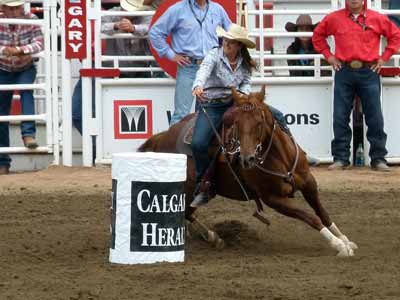A barrel racer sits deep in her saddle during a hard, fast turn
