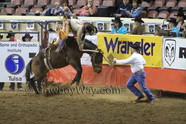 A saddle bronc rider bucks off over the front of the horse