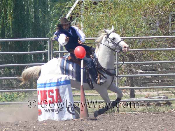 A cowboy mounted shooter rounds the far end of the course