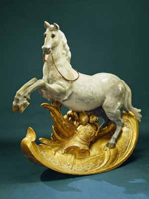 A very old wooden rocking horse with gilded stand