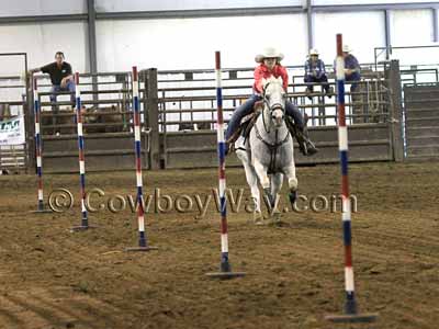 A horse and rider run a pole bending course