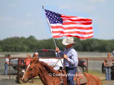 A mounted rider posts the American flag at a ranch rodeo
