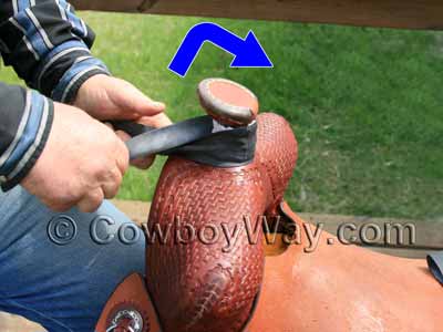 Twist the rubber then loop it up and over the saddle horn