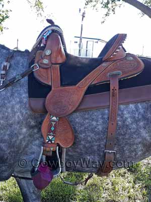 A Tammy Fischer treeless barrel racing saddle on a gray horse